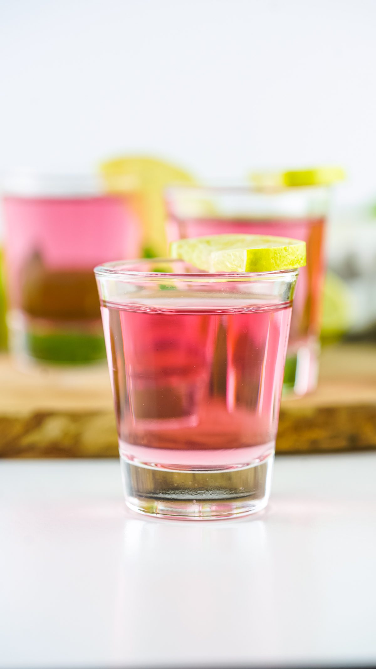 Shot glass with a vodka, cranberry juice and peach schnapps topped with a lime wedge