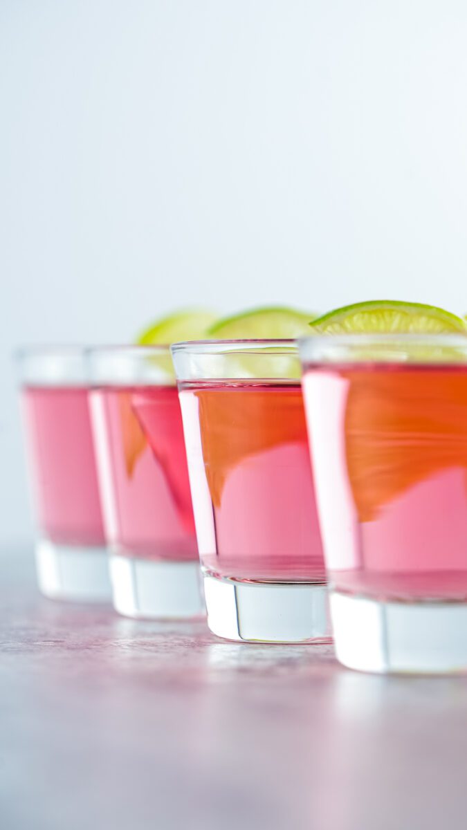 Shot glass with a vodka, cranberry juice and peach schnapps topped with a lime wedge